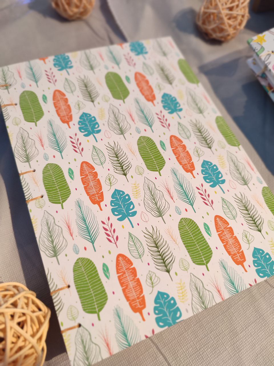 An image of handmade journal with vibrant leaves on a cover laying on a table